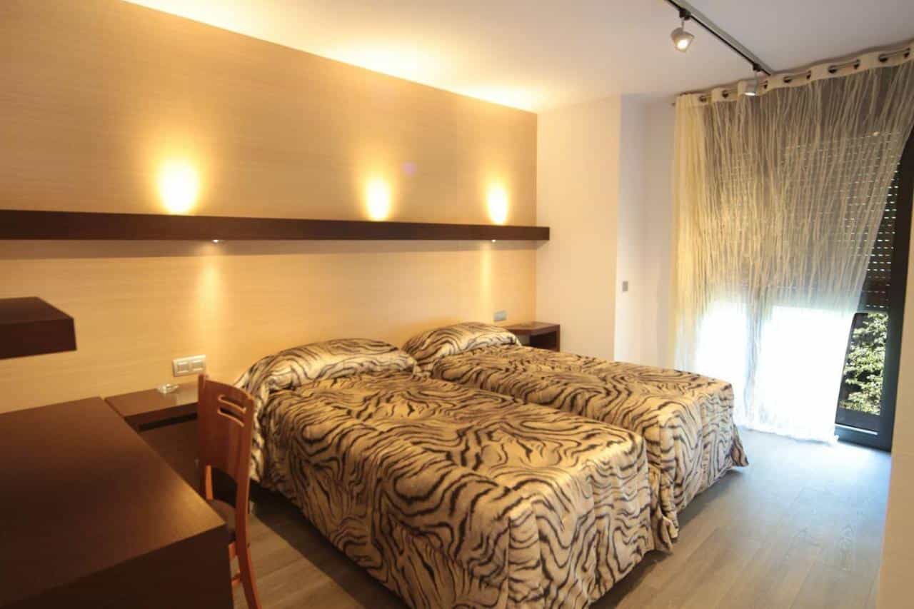 Twin hotel room with tiger-print bedding, modern lighting, and balcony access in Sant Antoni