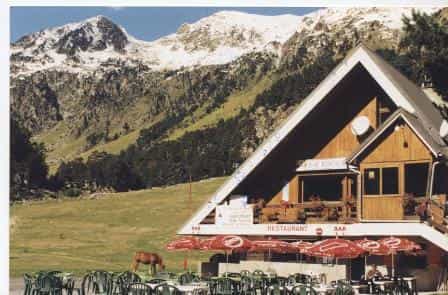 Chalet du Clot restaurant with outdoor seating below snow-capped mountains.