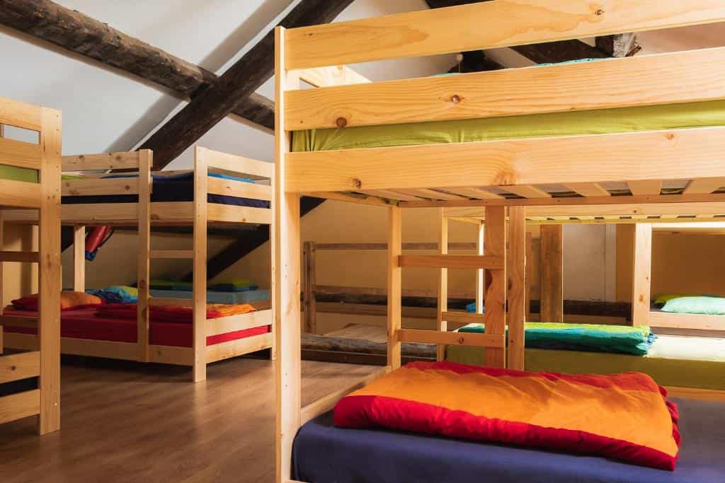 Wooden bunk beds with colorful bedding inside a room with exposed ceiling beams, Refugio Bujaruelo.