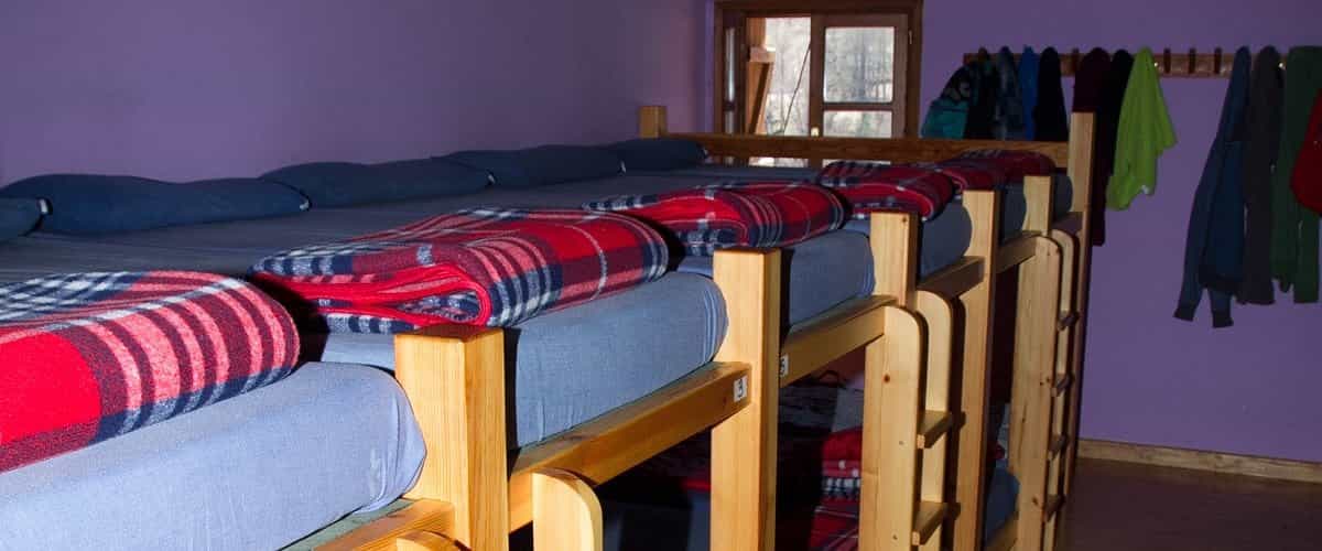 Bunk beds with blue mattresses and red plaid blankets inside a room with purple walls.