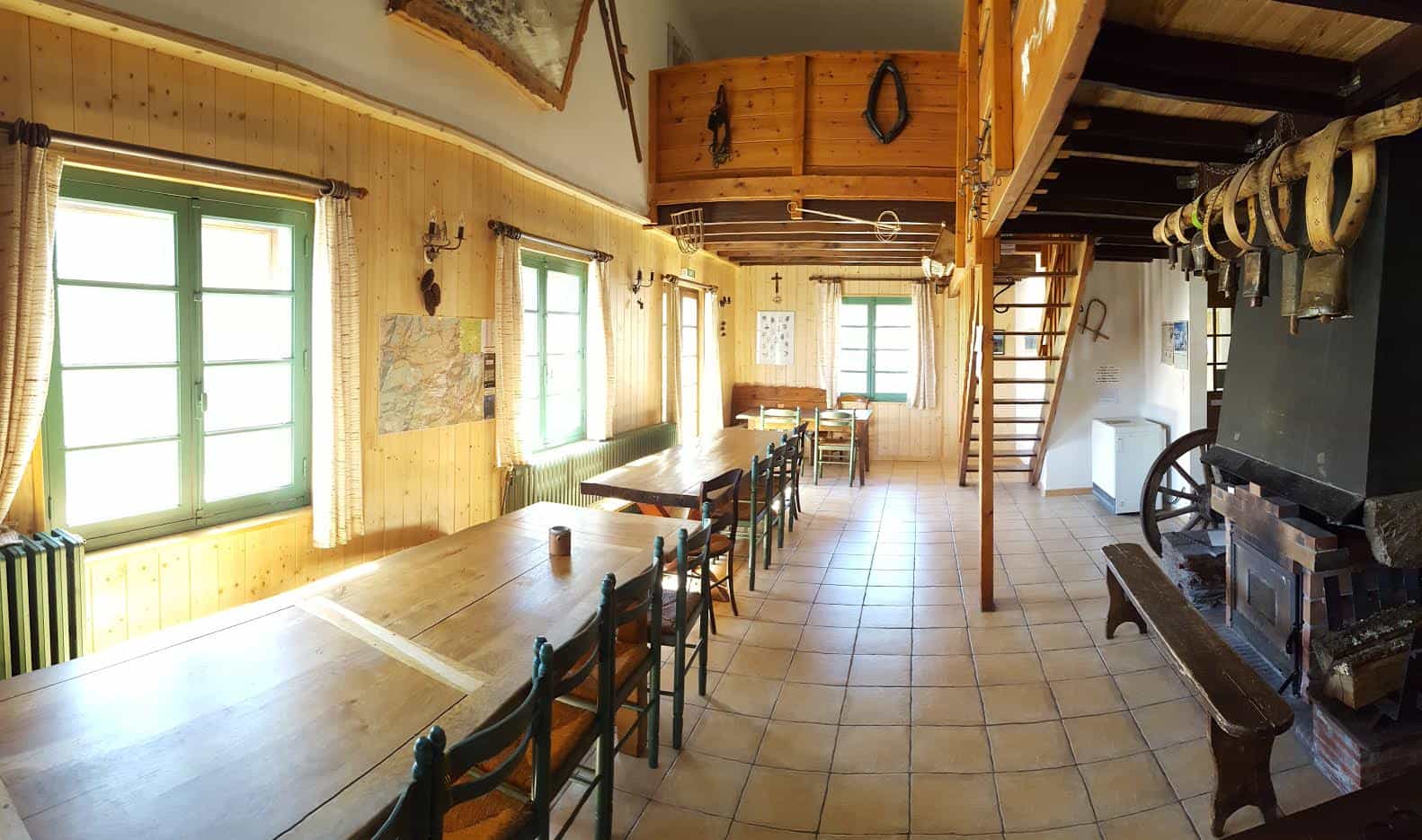 Rustic refuge dining hall with wood paneling, long tables, and a large stone fireplace.
