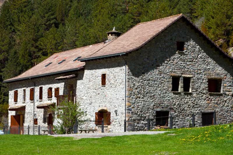 Stone building of Refugio de Bujaruelo in a mountain forest setting.