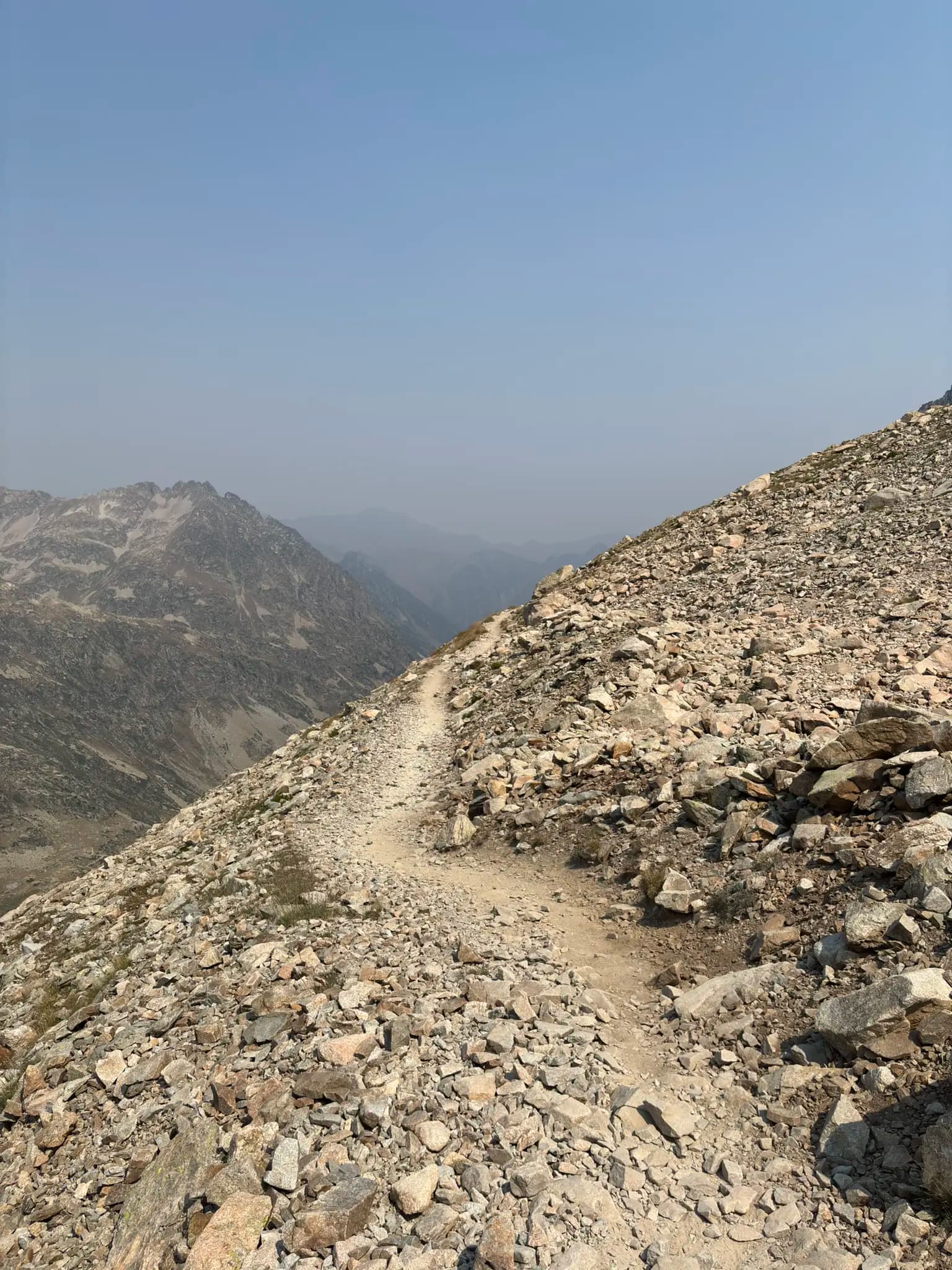 Hiking trail winding through a rocky mountain landscape with distant peaks.