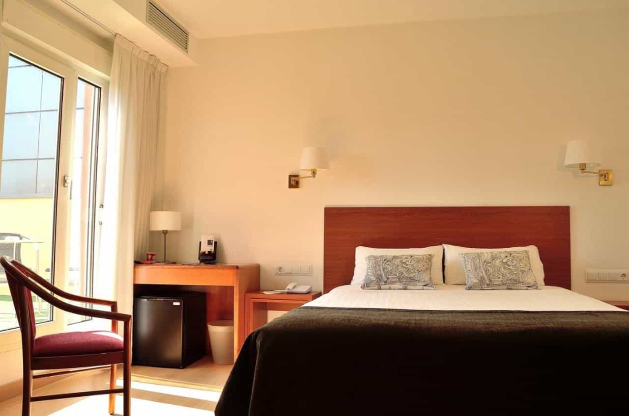 Hotel Ultonia room with bright natural light, wooden headboard, and balcony door.