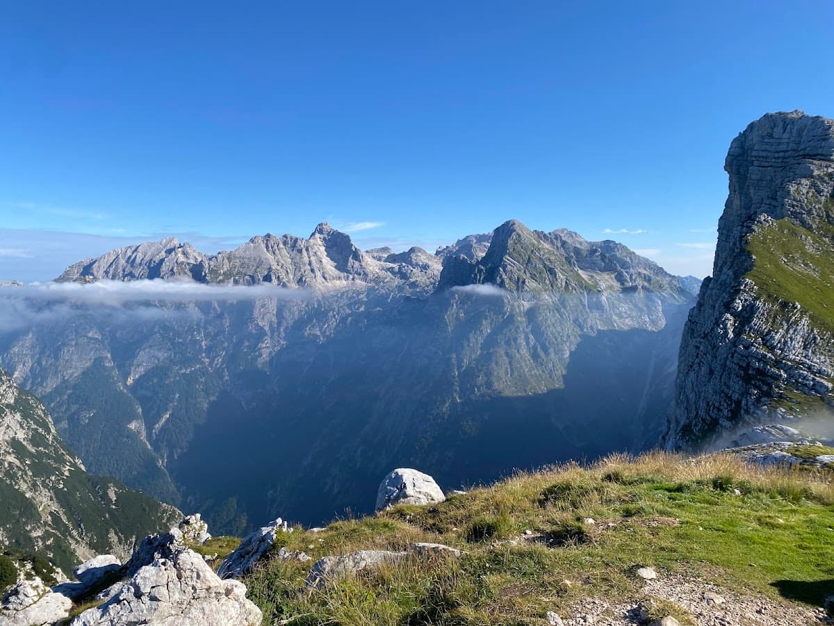 Rocky mountain peaks above a deep valley with low clouds under a clear blue sky
