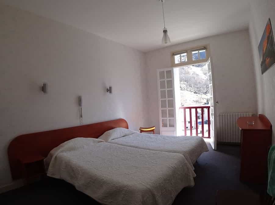 Twin hotel room with balcony view of a bare mountain slope in Hotel Compostelle.
