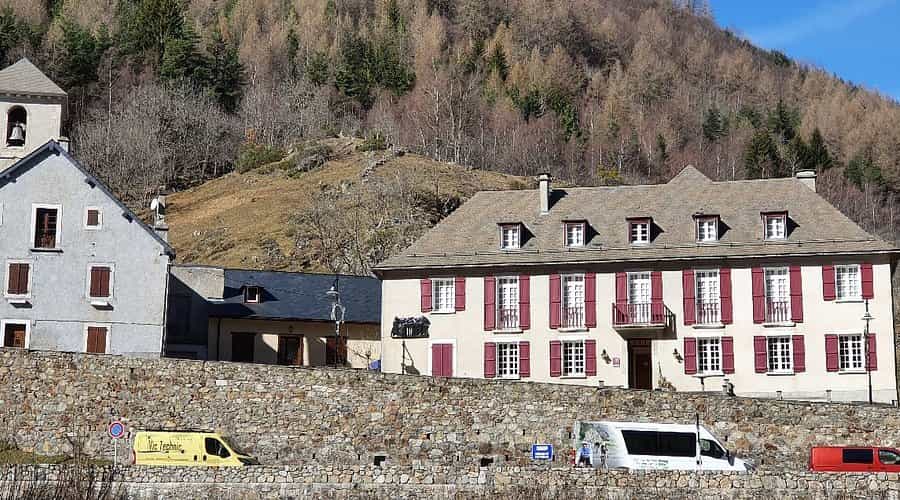 Buildings with stone retaining wall in a mountain village, Hotel Compostelle visible