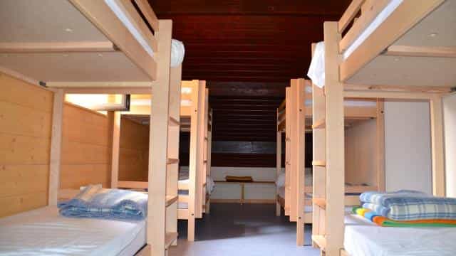 Wooden bunk beds in a dormitory room at Refuge Lac de l’Oule with blankets stacked on mattresses.