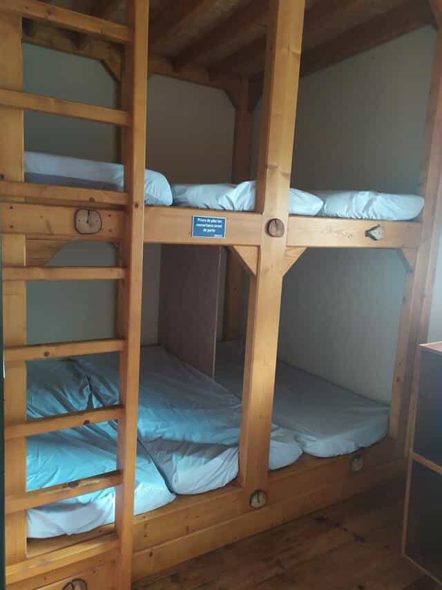 Wooden bunk beds with white bedding inside a refuge room at Le Refuge d'Espingo