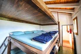 Wooden bunk beds with blue bedding inside a simple room at Refugi Prat d'Aguiló.