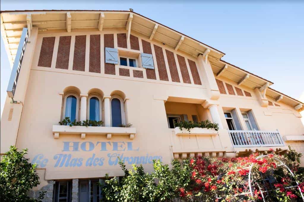 Hotel Le Mas des Citronniers building facade with arched windows and red flowering vines