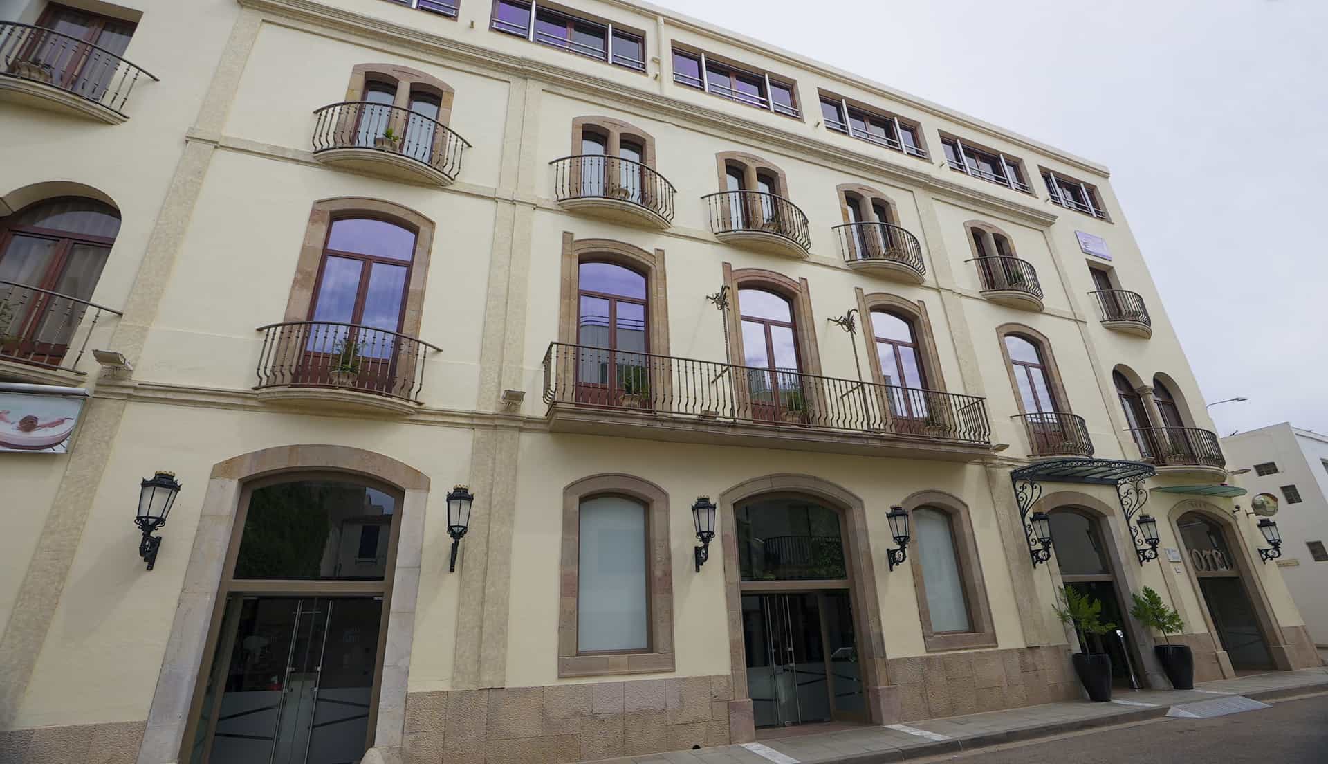 Hotel building facade in Porto Cristo with cream walls, arched windows, and wrought iron balconies.