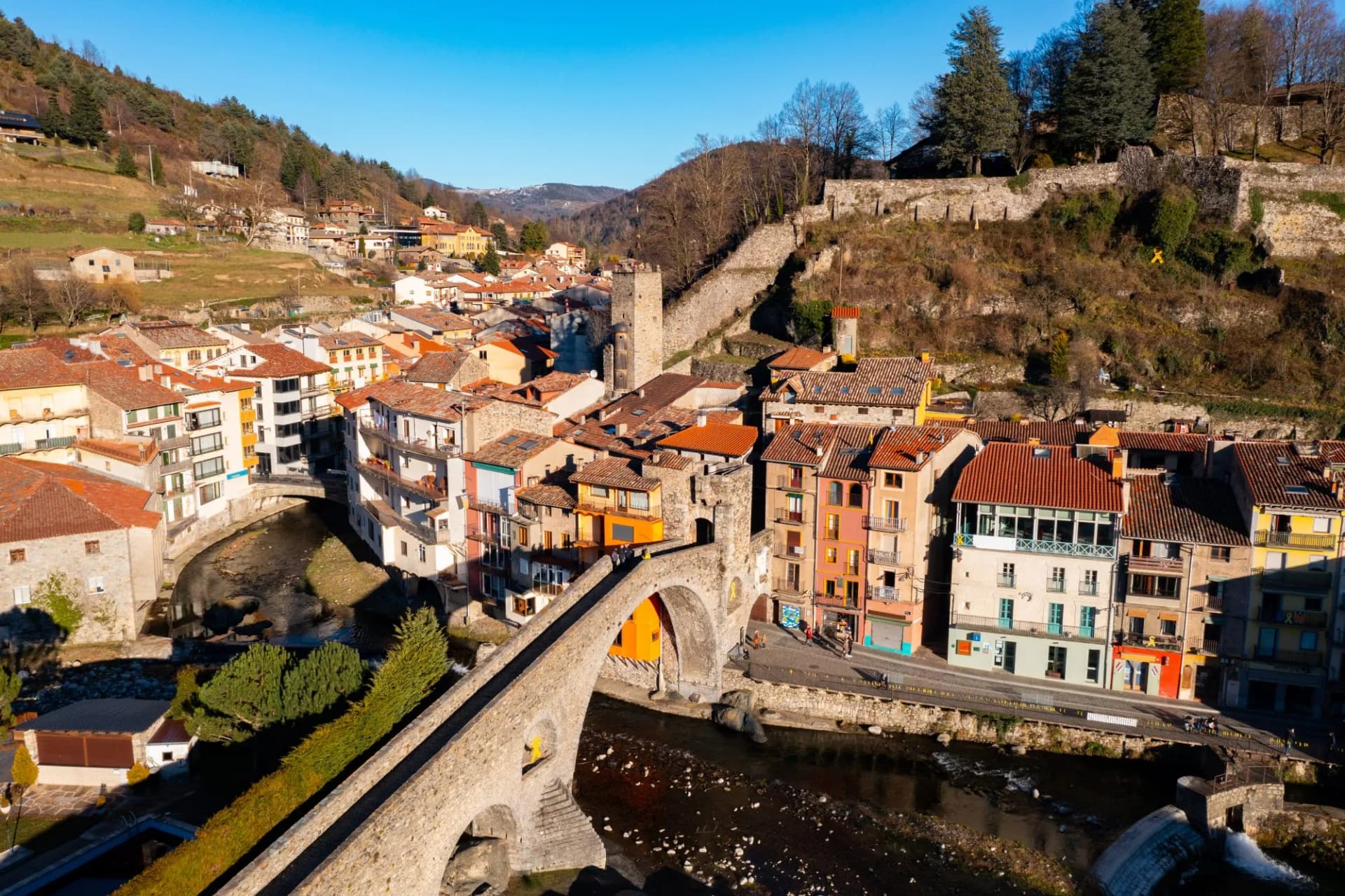 View of Camprodon town in Pyrenees with stone bridge over Ter river and autumn foliage.