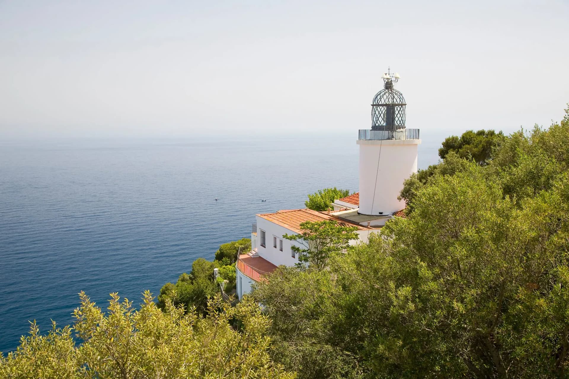 Sant Sebastià Lighthouse in Palafrugell, Spain, above blue Mediterranean sea.